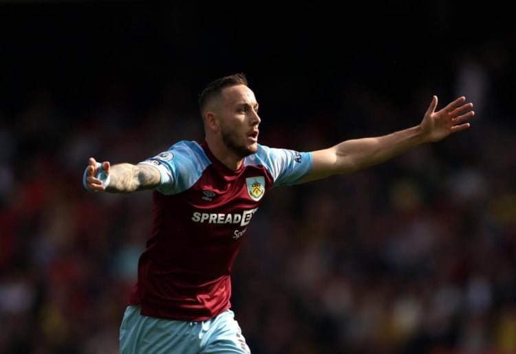 Josh Brownhill in action for Burnley with the midfielder holding his arms in the air.