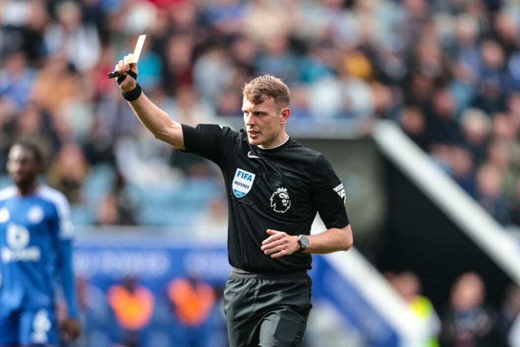 Premier League referee Sam Barrott showing a yellow card