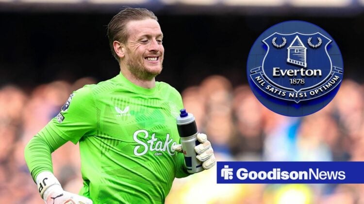 Jordan Pickford is smiling at the Everton badge.