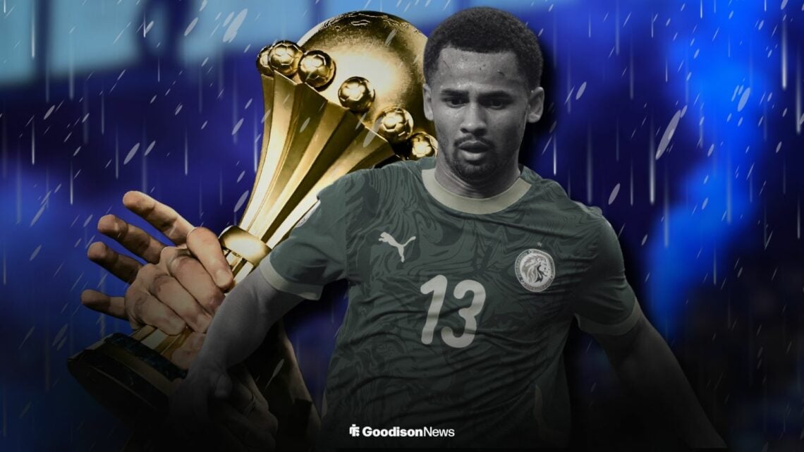 Iliman Ndiaye playing for Senegal standing infront of the AFCON trophy